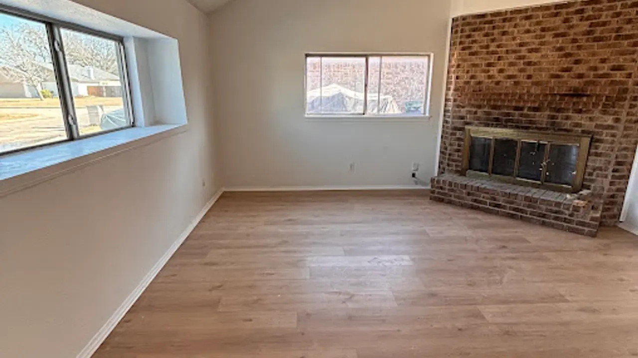 Clean living room with a brick fireplace and wood flooring